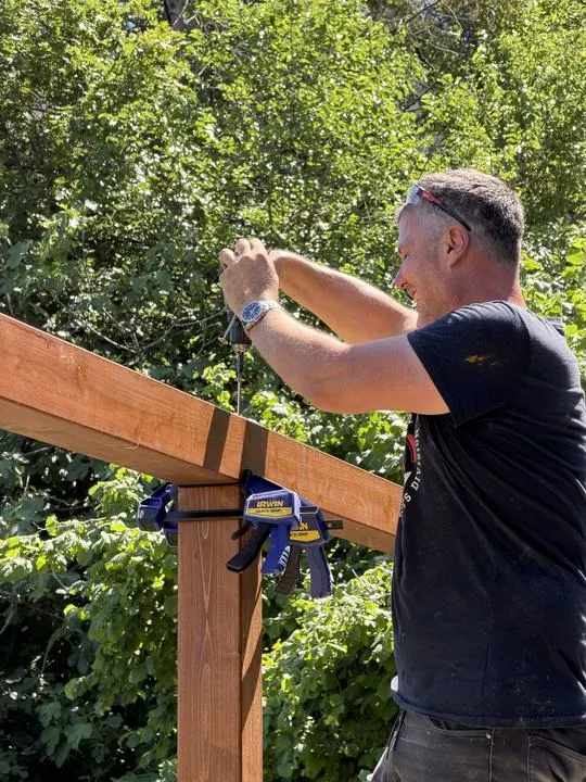 Asztalos létrán állva rögzíti a gerendát